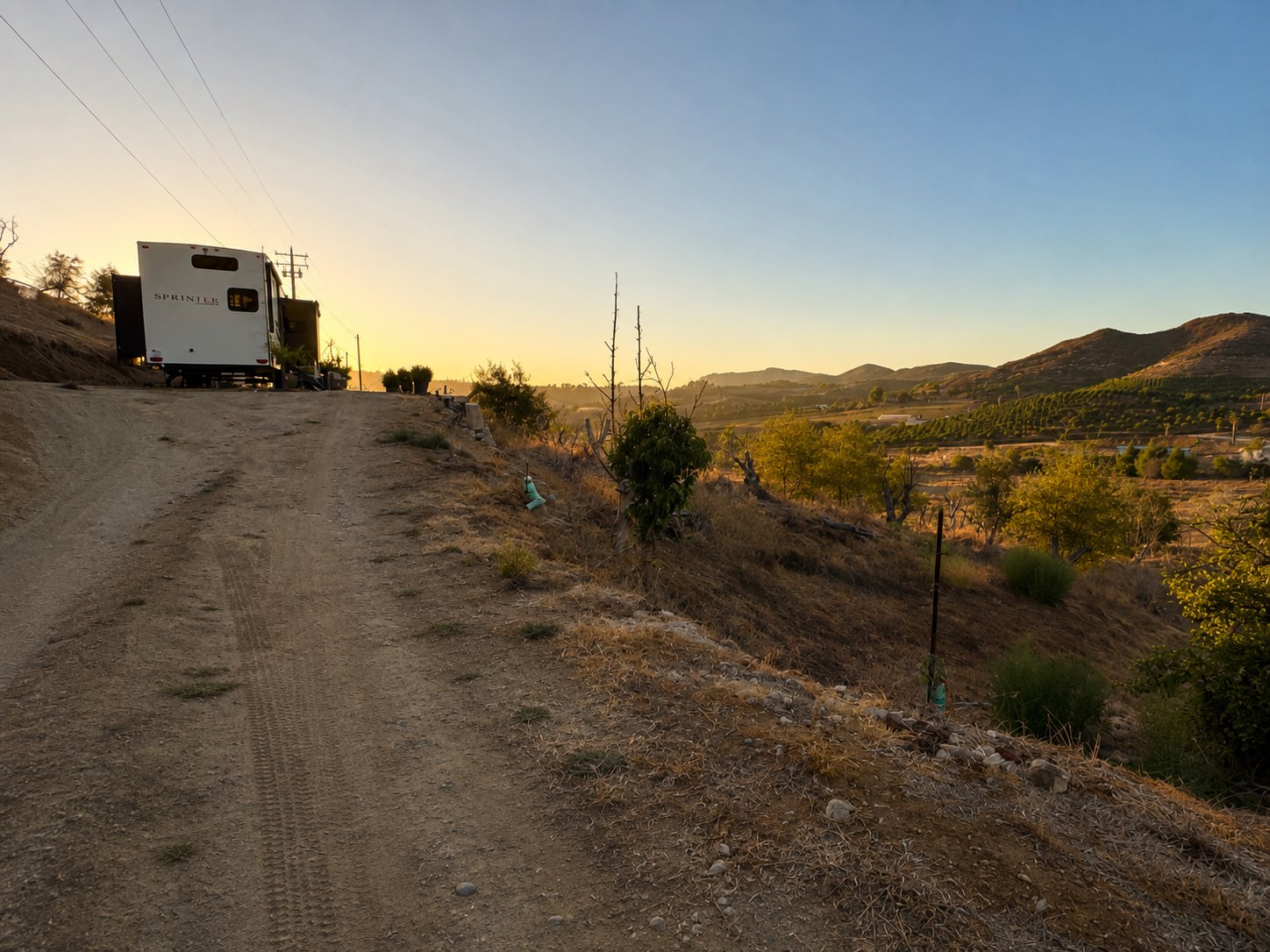 Dirt driveway leading up to the property at sunset