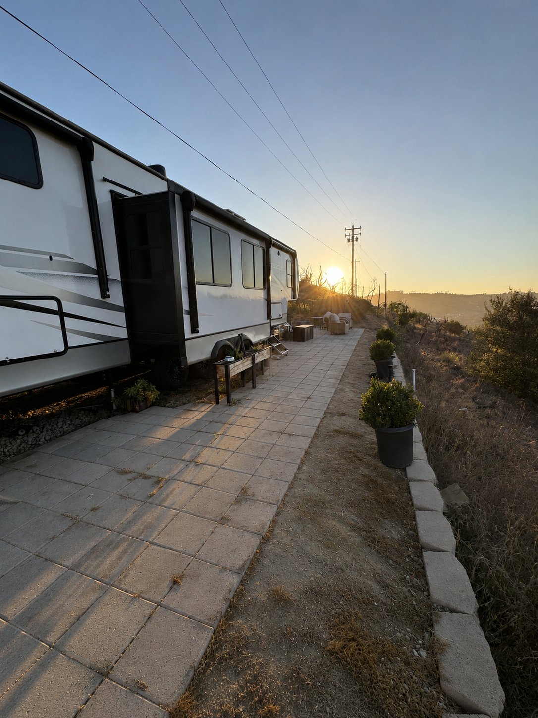 Exterior of the fifth-wheel at golden hour with paver patio and seating
